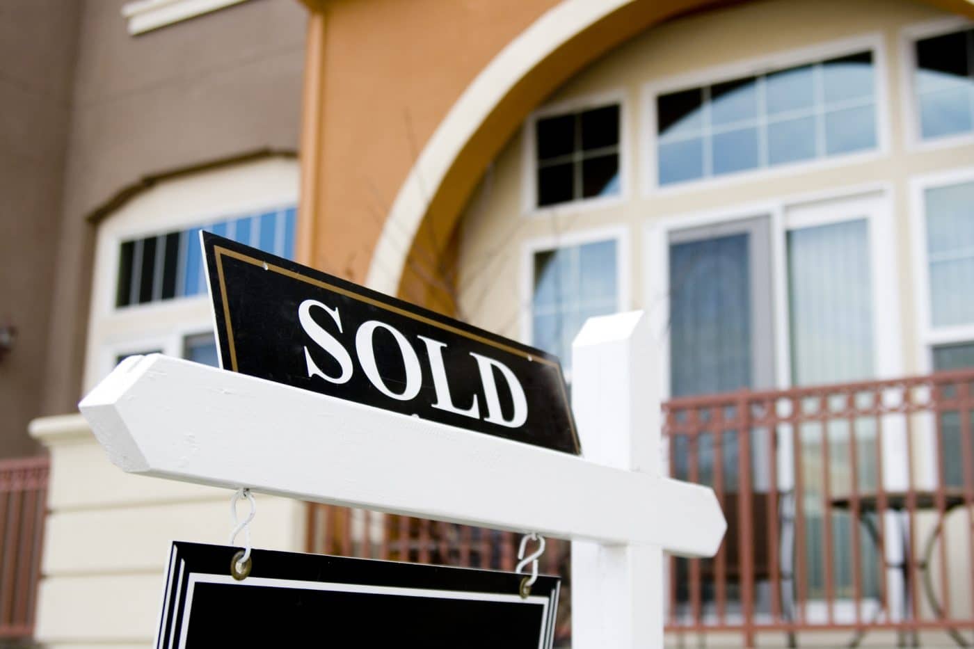 Charming home with a 'SOLD' sign atop the real estate 'For Sale' sign, representing a successful budget-conscious real estate purchase