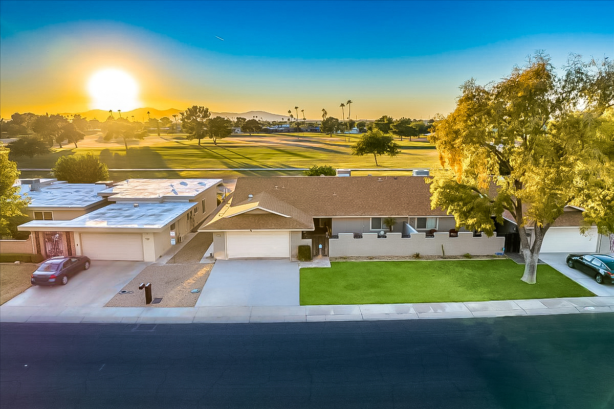 Aerial view of 18410 N 104th Avenue, Sun City, AZ, showcasing golf course frontage, mountain views, and sunset skies