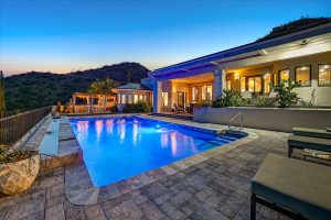 Twilight view of the illuminated salt water pool and outdoor seating area at 6432 E El Sendero Rd in Carefree, Arizona, with mountain views in the background.