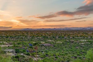 Panoramic view from 6432 E El Sendero Rd in Carefree, Arizona, overlooking the lush Sonoran Desert and distant mountain ranges at sunset.