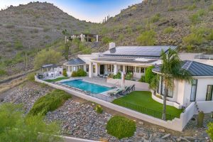 Aerial view of the backyard at 6432 E El Sendero Rd in Carefree, Arizona, showing a salt water pool, lounging areas, and rooftop solar panels against a desert mountain backdrop.