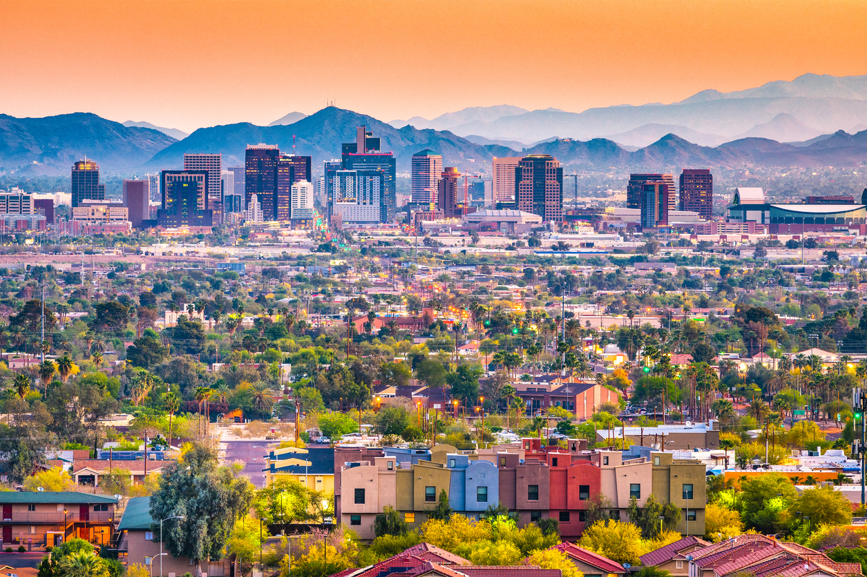 Buying a condo in Maricopa County — Phoenix skyline at sunset with colorful condos and townhomes in view.
