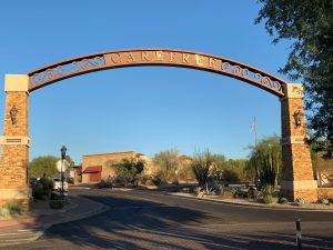 Carefree Arizona entrance arch over the downtown road with desert landscaping and shops in view.