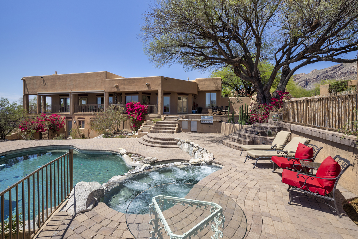 Southwestern-style Arizona home with backyard pool and desert landscaping, ideal for assessing home features during rain or storms.